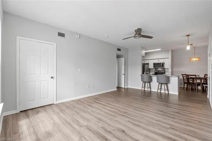 Unfurnished living room featuring baseboards, visible vents, light wood-type flooring, and a ceiling fan
