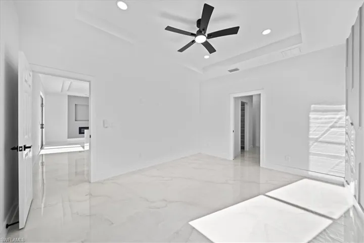 Unfurnished bedroom featuring light marble finish floors, recessed lighting, a ceiling fan, and a raised ceiling