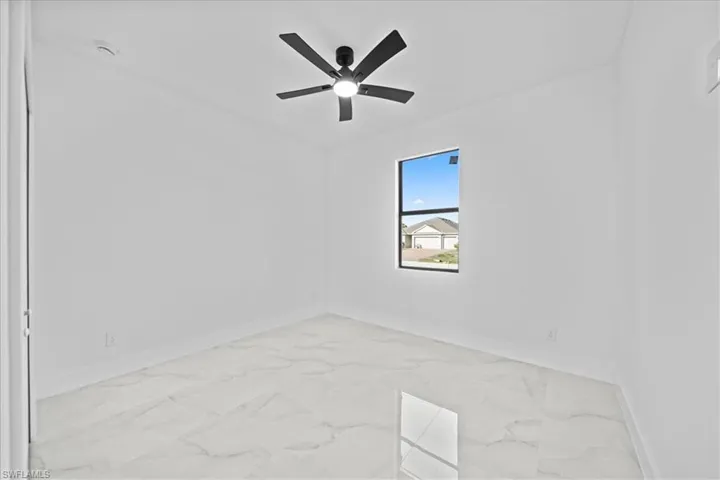 Empty room with light marble finish floors and ceiling fan