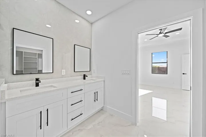 Full bath with double vanity, light marble finish floors, recessed lighting, and ceiling fan