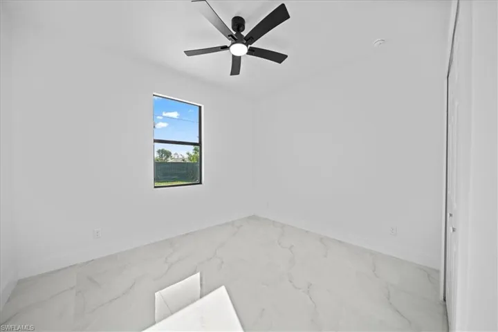 Empty room with light marble finish floors and ceiling fan