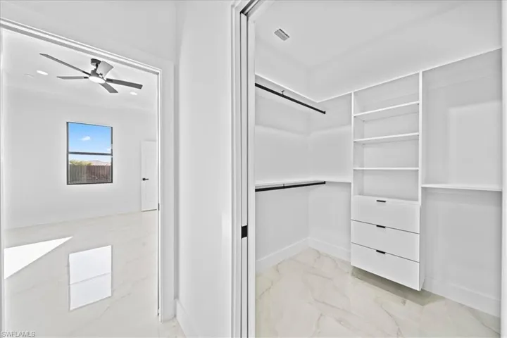 Walk in closet featuring light marble finish floors and ceiling fan