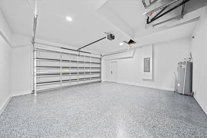 Garage featuring water heater, electric panel, and a garage door opener