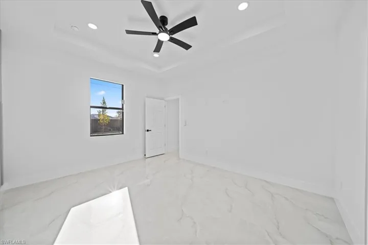 Unfurnished bedroom with ceiling fan, light marble finish flooring, recessed lighting, and a raised ceiling