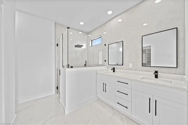 Full bathroom with double vanity, a shower stall, recessed lighting, and light marble finish floors