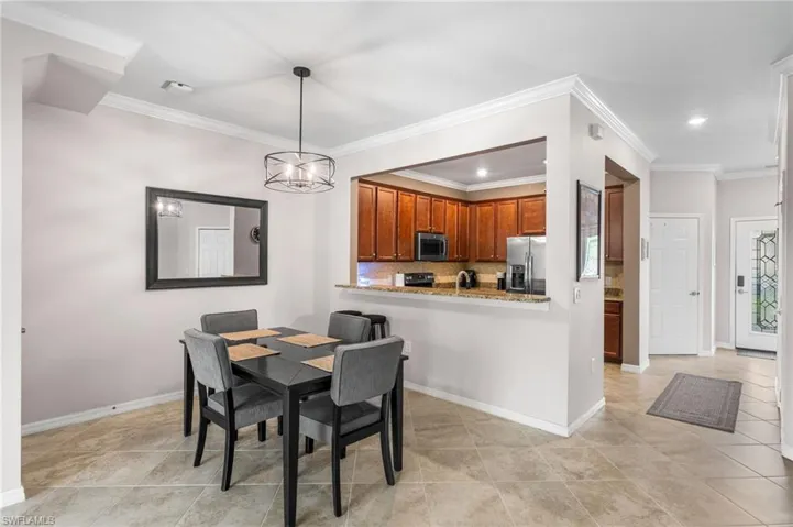 Dining area with an inviting chandelier, ornamental molding, and light tile patterned floors
