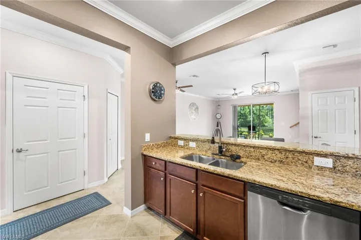 Kitchen with sink, light tile patterned floors, light stone countertops, dishwasher, and ceiling fan