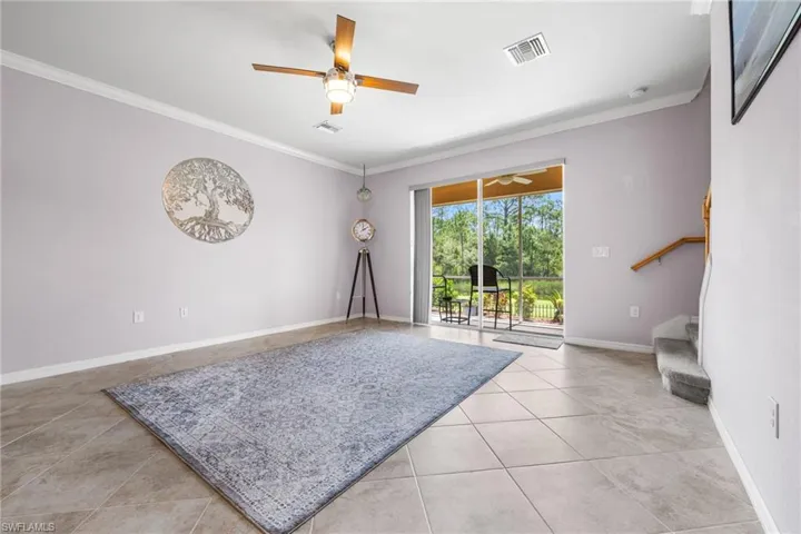 Living room featuring crown molding, ceiling fan, and light tile patterned floors