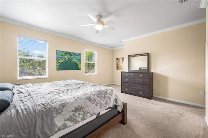 Carpeted bedroom with ceiling fan and ornamental molding