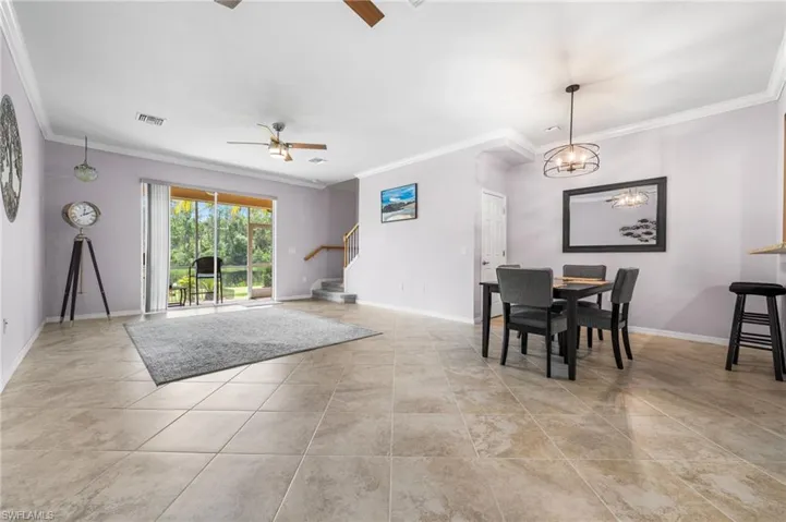 Dining room featuring ceiling fan with notable chandelier, crown molding, and light tile patterned floors