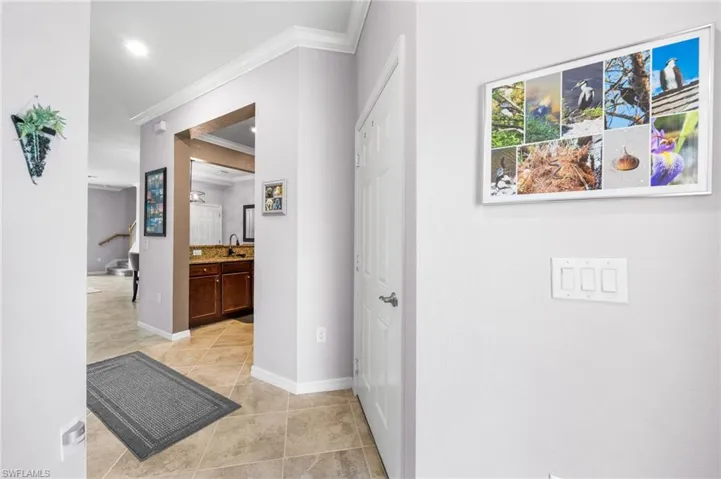 Entry hall with sink, ornamental molding, and light tile patterned floors