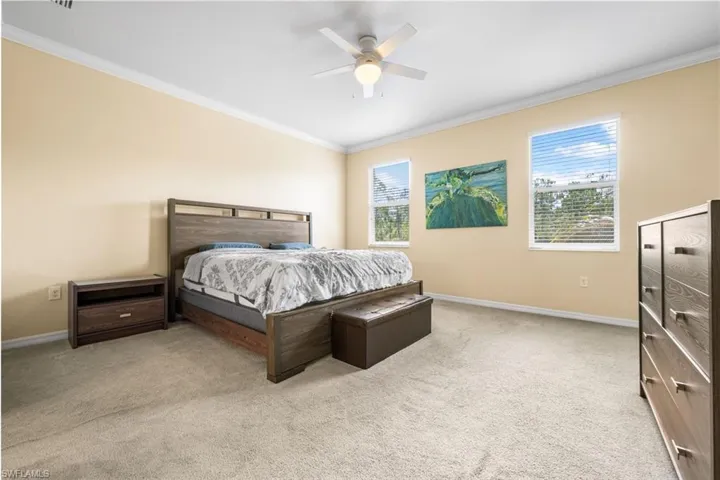 Bedroom featuring light carpet, multiple windows, ceiling fan, and crown molding