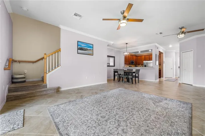 Tiled living room with crown molding and ceiling fan