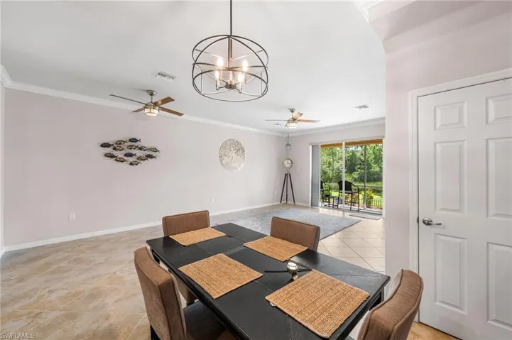 Tiled dining room featuring ceiling fan with notable chandelier and crown molding
