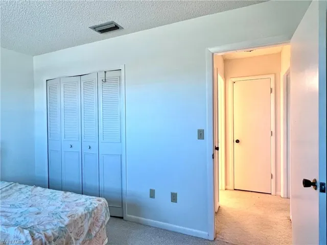 Bedroom featuring carpet floors, a textured ceiling, and a closet