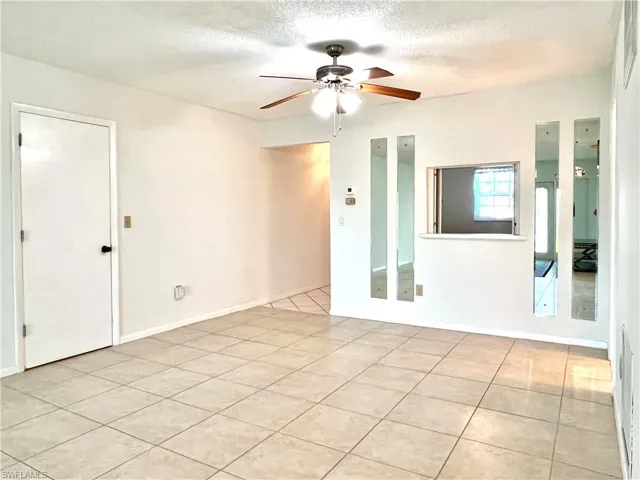 Spare room with light tile patterned floors, a textured ceiling, and ceiling fan