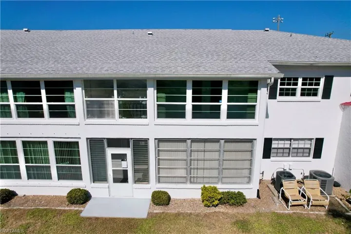Back of property with stucco siding, a shingled roof, and a patio