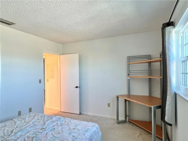 Bedroom featuring light colored carpet and a textured ceiling