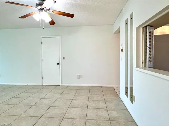 Unfurnished room with a textured ceiling, light tile patterned flooring, and ceiling fan