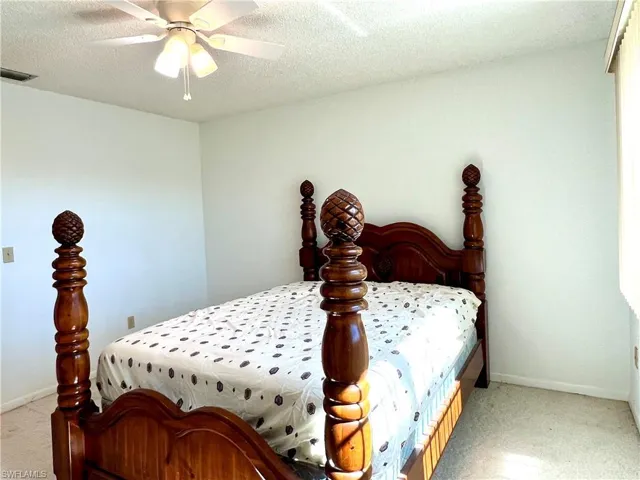 Bedroom featuring a textured ceiling, a ceiling fan, and light colored carpet