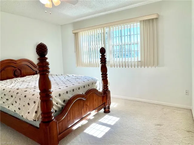 Bedroom featuring carpet flooring, multiple windows, a textured ceiling, and a ceiling fan