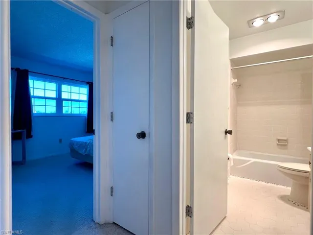 Bathroom with shower / washtub combination, connected bathroom, and tile patterned flooring