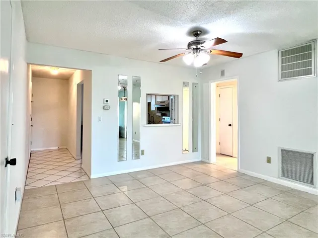 Empty room with light tile patterned floors, a textured ceiling, and ceiling fan