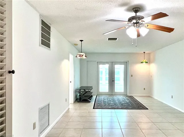 Doorway featuring french doors, tile patterned floors, a textured ceiling, and a ceiling fan