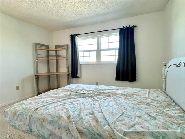 Carpeted bedroom featuring a textured ceiling and baseboards