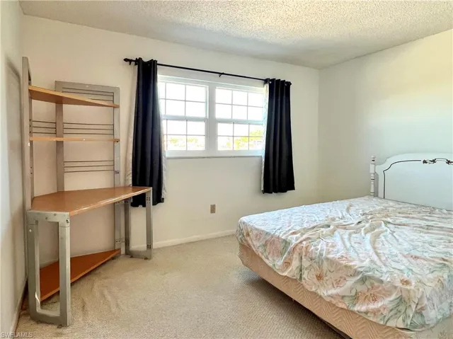 Carpeted bedroom with a textured ceiling and baseboards