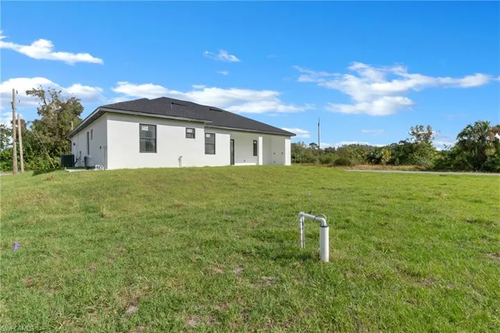 Back of property with central air condition unit and a yard
