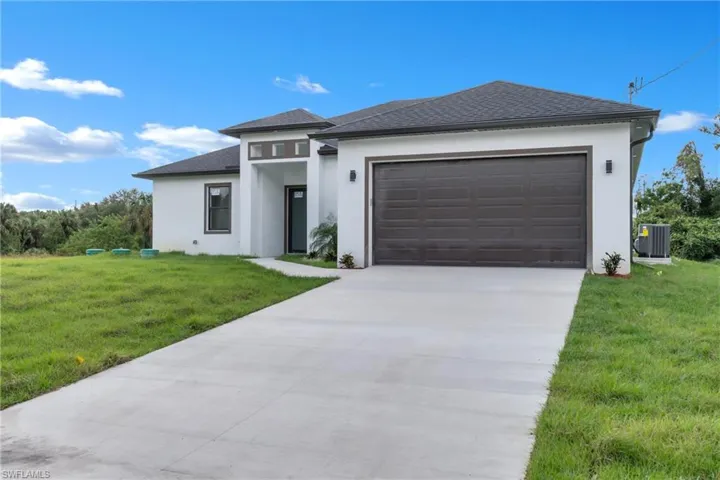 Prairie-style house featuring a garage, cooling unit, and a front lawn