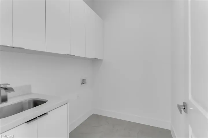 Clothes washing area featuring washer hookup, cabinets, and sink