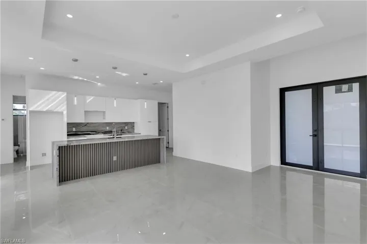 Kitchen featuring white cabinetry, a raised ceiling, and a kitchen island with sink