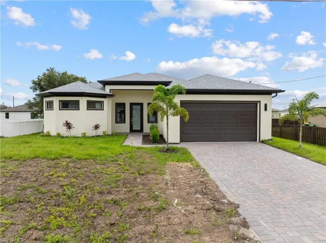Prairie-style house featuring decorative driveway, stucco siding, and an attached garage