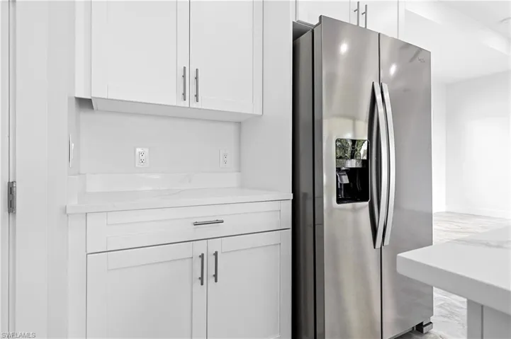 Kitchen with stainless steel refrigerator with ice dispenser, light countertops, and white cabinetry