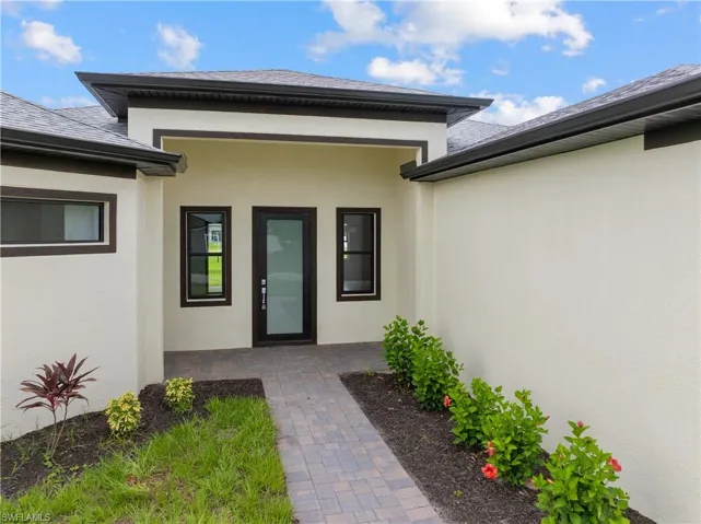 Property entrance with stucco siding and a shingled roof