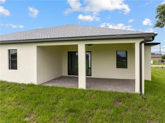 Rear view of property with a patio area, a lawn, and stucco siding