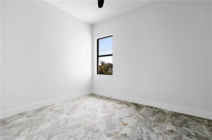 Spare room featuring marble finish floors and a ceiling fan