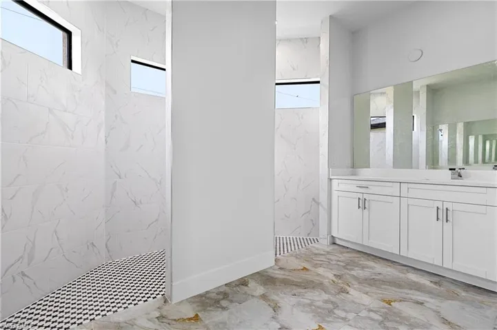 Bathroom featuring walk in shower, marble tiled floors, and vanity