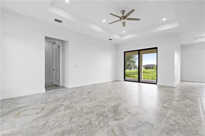 Unfurnished room with a tray ceiling, recessed lighting, light marble finish flooring, and ceiling fan