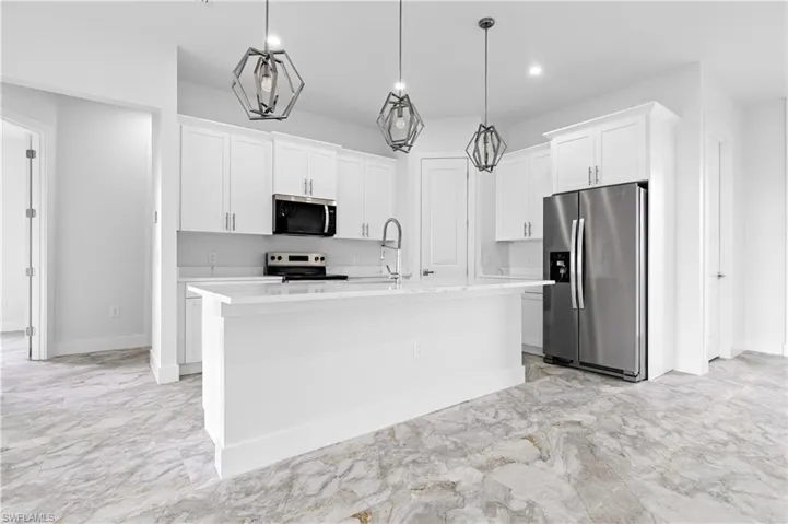 Kitchen featuring appliances with stainless steel finishes, white cabinetry, light marble finish flooring, light countertops, and recessed lighting