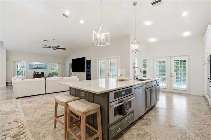 Kitchen with french doors, a kitchen bar, plenty of natural light, pendant lighting, and lofted ceiling