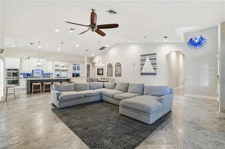 Living area with a chandelier, a ceiling fan, lofted ceiling, recessed lighting, and arched walkways
