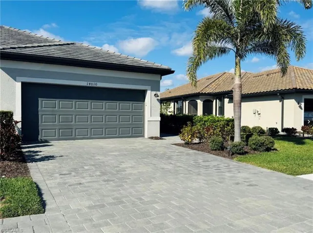 View of front of home with decorative driveway, stucco siding, a tiled roof, and an attached garage