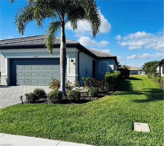Front of home featuring driveway, stucco siding, a yard, an attached garage, and a tile roof