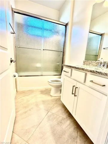 Full bathroom featuring vanity, shower / bath combination with glass door