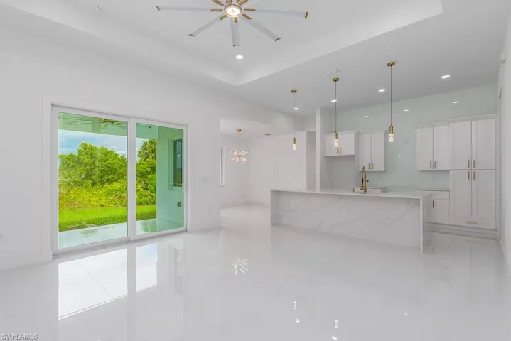 Kitchen featuring white cabinets, plenty of natural light, a tray ceiling, and light tile floors