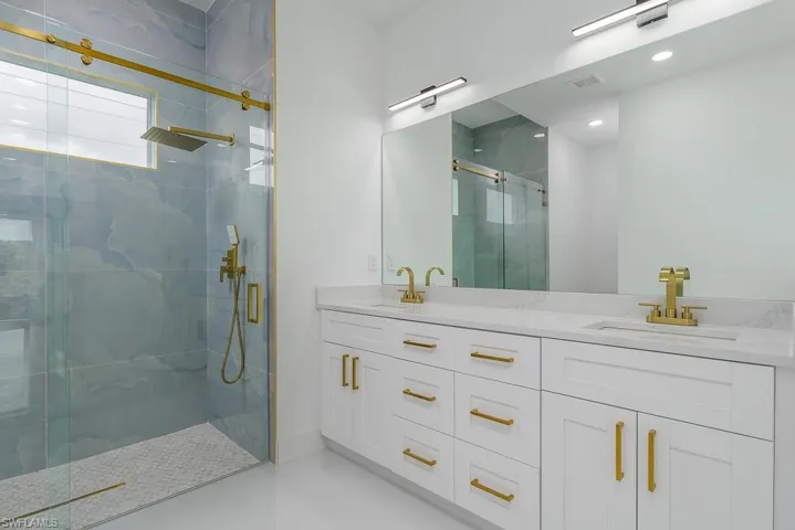 Bathroom featuring walk in shower, large vanity, tile flooring, and double sink