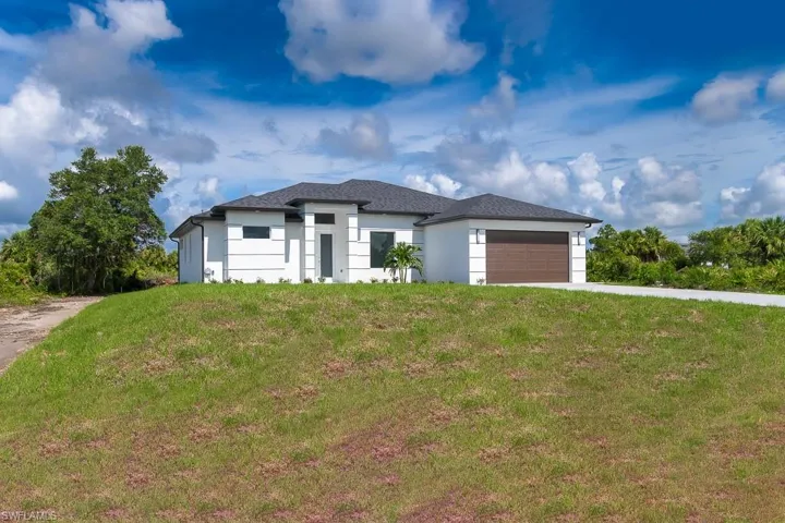 View of front facade featuring a garage and a front lawn
